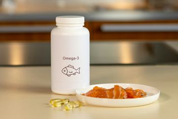 Enhance Men's Health: Omega-3 Supplements and Fresh Salmon for Optimal Well-being Bottle of Omega-3 supplements for men alongside fresh salmon fillet on a cutting board